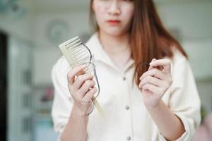 Asian woman have problem with long hair loss attach to comb brush. photo