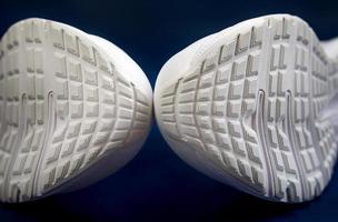 la suela blanca de las zapatillas de deporte sobre un fondo azul oscuro. un par de zapatillas blancas. foto