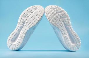 Sporting white sneakers on a blue background. View from the sole side. photo