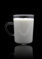 vaso de leche aislado en suelo reflectante y fondo negro foto