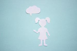 The silhouette of a girl in a dress and with ponytails made of white paper, cut by hand. With speech-bubble in the center of the photo