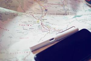 Map, map of Washington state, pen, glasses, cell phone, coffee cup on the table. photo