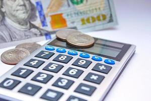 Calculator and dollar bills are placed on a white table. photo