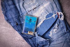 WASHINGTON USA - September 30 2022  Nirvana's cassette tape and Ripped jeans or Torn jeans. A symbol of the grunge or Seattle sound. photo