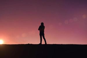 hombre caminando en la montaña con un fondo de puesta de sol en verano foto