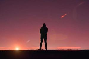 hombre caminando en la montaña con un fondo de puesta de sol en verano foto