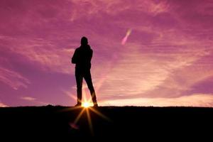 hombre caminando en la montaña con un fondo de puesta de sol en verano foto