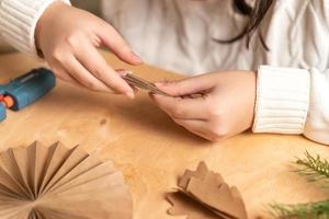 girl makes Christmas tree decorations out of paper with her own hands. step 3. step-by-step instruction photo