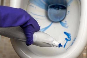 The cleaner's hands wash the toilet bowl in the bathroom with detergent and rubber gloves photo
