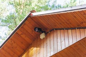 Surveillance camera on the roof of a private wooden house photo