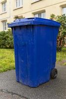Plastic blue garbage container in the courtyard of a residential building photo
