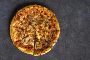 Delicious warm pizza on a gray-black background. Top view of a delicious baked hot pizza photo