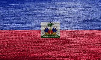 bandera de la república de haití sobre la textura de la superficie del agua con pequeñas ondas. foto