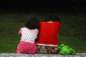 Magelang, Indonesia, 2022 - photo of 2 little sisters and sisters who are on the edge of the park in the afternoon