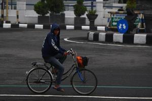 Magelang, Indonesia, 2022 - photo of old man riding a bicycle on the side of the road in the afternoon