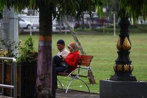 Magelang, Indonesia, 2022 - Photo of a husband and wife sitting on a park bench, in the afternoon
