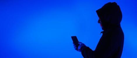 Digital security Concept. Anonymous hacker with mask holding smartphone hacked. photo