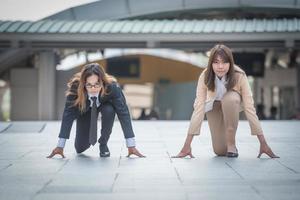 2023 new start, two business woman getting ready for race in business on the city background, business competition concepts. photo