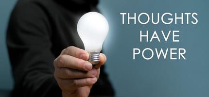 Hand holding light bulb with text Thoughts Have Power, The power of thinking ideas, think big. photo