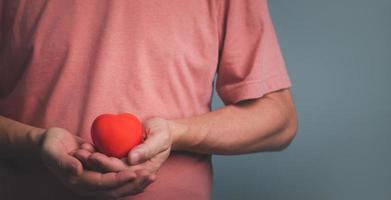 Hands holding and giving red heart for love, health care, organ donation, world heart day, world health day, mindfulness, well being, family insurance concept. photo