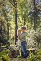 A cute boy is playing with a bear cub in the forest. The sun's rays envelop the space of the clearing with a stump. A magical story of interactions for the book. Space for copying. Selective photo