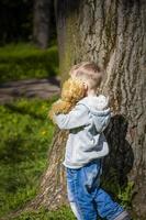 un chico lindo está jugando con un cachorro de oso en el bosque. los rayos del sol envuelven el espacio. una historia mágica de interacciones para el libro. espacio para copiar. foto