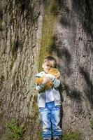 un chico lindo está jugando con un cachorro de oso en el bosque. los rayos del sol envuelven el espacio. una historia mágica de interacciones para el libro. espacio para copiar. foto