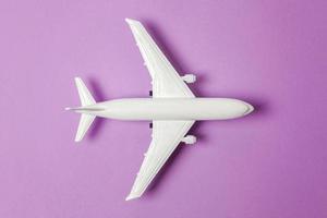 simplemente diseño plano, modelo de juguete en miniatura, avión sobre fondo de moda de papel de colores pastel púrpura violeta. viaje en avión vacaciones fin de semana de verano viaje de aventura en el mar billete de viaje concepto de viaje. foto
