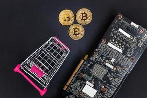 Cryptocurrency golden bitcoin coin lying in shopping cart and video card. Electronic virtual money for web banking and international network payment. Symbol of crypto virtual currency. Mining concept. photo