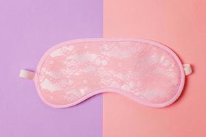 Sleeping eye mask, isolated on violet and pink pastel colorful trendy geometric background. Do not disturb me, let me sleep. Rest, good night, insomnia, relaxation, tired, travel concept. photo