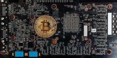Cryptocurrency golden bitcoin coin lying on video card. Electronic virtual money for web banking and international network payment. Symbol of crypto virtual currency. Mining concept. photo