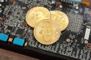 Cryptocurrency golden bitcoin coin lying on video card. Electronic virtual money for web banking and international network payment. Symbol of crypto virtual currency. Mining concept. photo