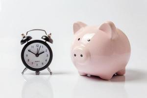 Pink piggy bank and classic alarm clock isolated on white background. Saving time investment budget wealth business retirement, financial, money, banking concept. Copy space. photo