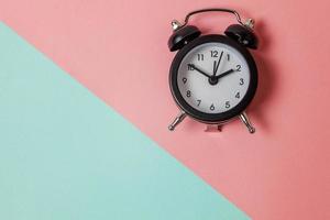 Ringing twin bell vintage classic alarm clock on blue pink pastel colorful trendy geometric background. Rest hours time of life good morning night wake up awake concept. Flat lay top view copy space. photo