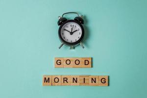 Simply flat lay design alarm clock and Inscription GOOD MORNING letters word on blue pastel colorful trendy background. Breakfast time. Good morning wake up awake concept. Top view copy space. photo