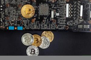 Cryptocurrency golden silver bitcoin coin lying on video card. Electronic virtual money for web banking and international network payment. Symbol of crypto virtual currency. Mining concept. photo