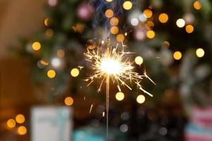 velas de bengalas brillantes de navidad se queman en el fondo del árbol de navidad. decoración de iluminación navideña en el interior de la casa. luces de chispas mágicas festivas para fiestas navideñas. Nochebuena con fuegos artificiales. foto