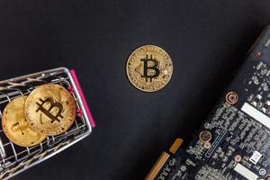 Cryptocurrency golden bitcoin coin lying in shopping cart and video card. Electronic virtual money for web banking and international network payment. Symbol of crypto virtual currency. Mining concept. photo