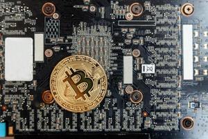 Cryptocurrency golden bitcoin coin lying on video card. Electronic virtual money for web banking and international network payment. Symbol of crypto virtual currency. Mining concept. photo