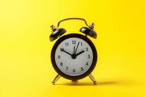 Ringing twin bell vintage classic alarm clock isolated on yellow colourful trendy modern fashion background. Rest hours time of life good morning night wake up awake concept. Copy space. photo