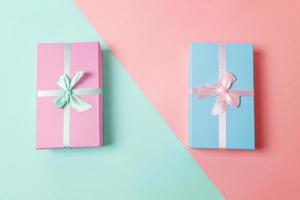 Small gift box wrapped pink and blue paper isolated on blue and pink pastel colorful trendy geometric background. Christmas New Year birthday valentine celebration present romantic concept. photo