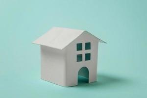 Simply design with miniature white toy house isolated on blue pastel colourful trendy background. Mortgage property insurance dream home concept. Copy space. photo