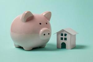 Simply design with miniature toy house, piggy bank isolated isolated on blue pastel colourful trendy background. Mortgage property insurance dream home banking investment loan concept. Copy space. photo