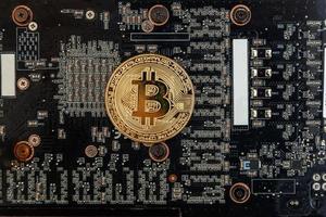 Cryptocurrency golden bitcoin coin lying on video card. Electronic virtual money for web banking and international network payment. Symbol of crypto virtual currency. Mining concept. photo