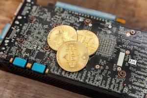 Cryptocurrency golden bitcoin coin lying on video card. Electronic virtual money for web banking and international network payment. Symbol of crypto virtual currency. Mining concept. photo