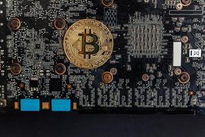 Cryptocurrency golden bitcoin coin lying on video card. Electronic virtual money for web banking and international network payment. Symbol of crypto virtual currency. Mining concept. photo