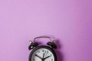 Ringing twin bell vintage classic alarm clock Isolated on purple violet pastel colourful background. Rest hours time of life good morning night wake up awake concept. Flat lay top view copy space. photo