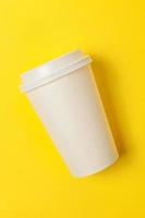 Simply flat lay design paper coffee cup on yellow colorful trendy background. Takeaway drink container. Good morning wake up awake concept. Template of drink mockup. Top view copy space. photo