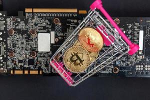 Cryptocurrency golden bitcoin coin lying in shopping cart and video card. Electronic virtual money for web banking and international network payment. Symbol of crypto virtual currency. Mining concept. photo