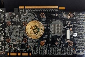 Cryptocurrency golden bitcoin coin lying on video card. Electronic virtual money for web banking and international network payment. Symbol of crypto virtual currency. Mining concept. photo